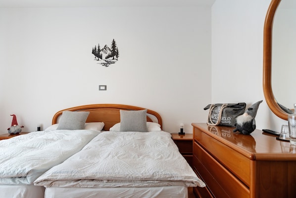 A bedroom with a bed, a dresser, a nightstand, a mirror, and a wall decal.