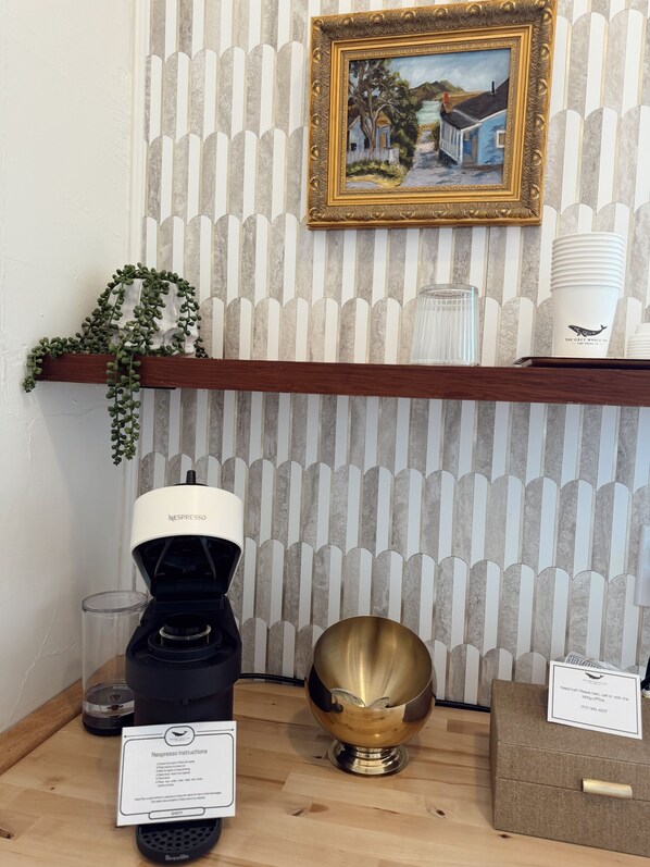 A Nespresso coffee machine, a brass bowl, and a framed picture on a shelf.