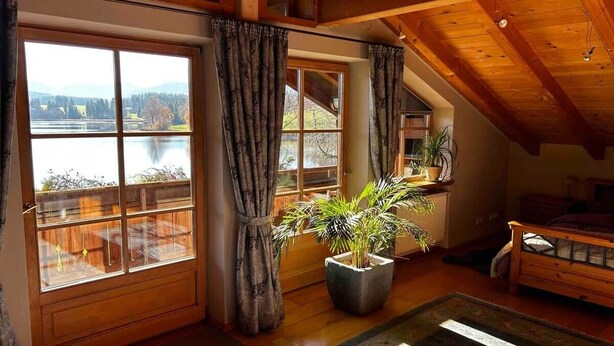 A room with large windows, wooden beams, and a potted plant. - Lake and Mountain view (Seeg)