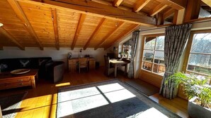 A wooden interior with a dining area, sofa, and large windows. - Lake and Mountain view (Seeg)