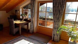 A dining area with a table, chairs, and a view of a lake through large windows. - Lake and Mountain view (Seeg)