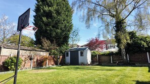 A backyard with a basketball hoop, a shed, and a tall tree. - Spacious 4-Bedroom Detached House with Garden and EV Charger (Sale)