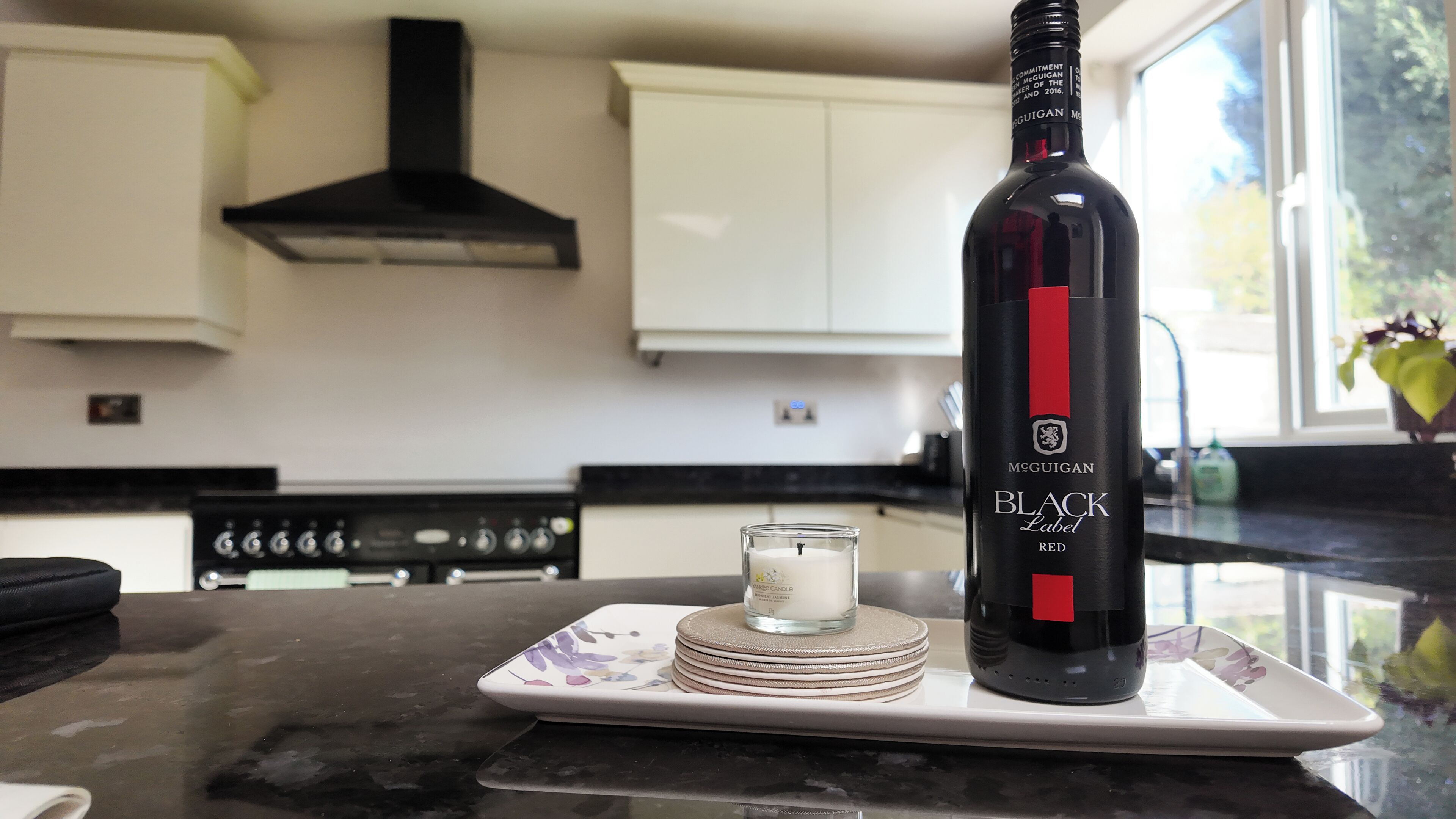 Une cuisine avec une bouteille de vin, une bougie et une assiette.
