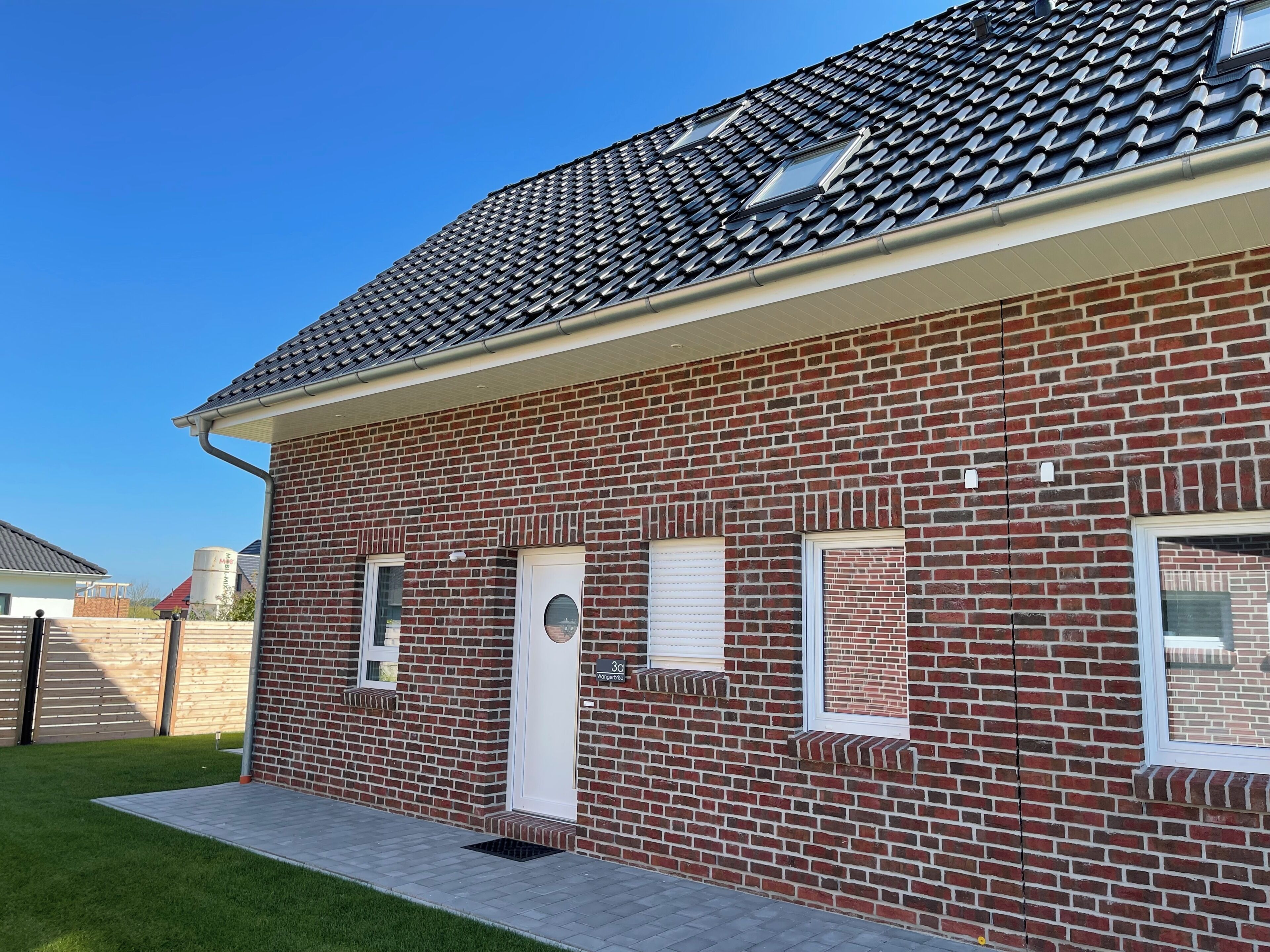 Een gebouw van baksteen met een pannendak, een voordeur en twee ramen.