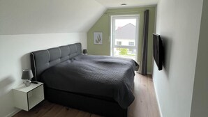 Una camera da letto con un letto, un comodino, una lampada e una TV fissata al muro.