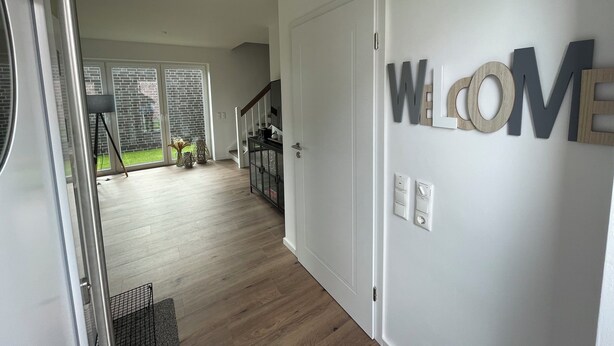 Un interno moderno con un cartello 'WELCOME', una scala e vista su un balcone.