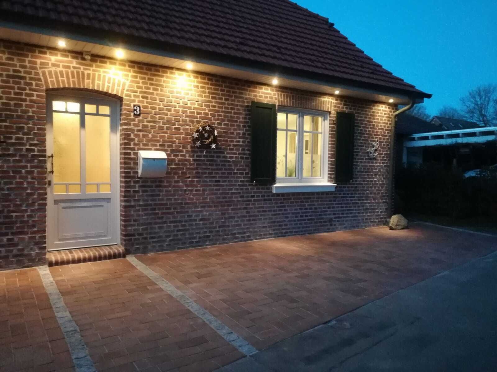 A brick house with a white door, a mailbox, and a small window with shutters.