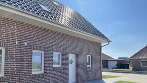 A residential building with a brick facade, a flat roof, and a small front yard with artificial grass. - Modern vacation home just 100 m from the Wangermeer with two bedrooms, smart TVs, fiber optics and terrace - perfect for families and those seeking relaxation. (Wangerland)