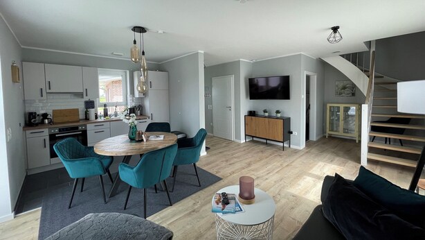 A modern open-plan living space with a kitchen, dining area, and a staircase leading to a loft. - Modern vacation home just 100 m from the Wangermeer with two bedrooms, smart TVs, fiber optics and terrace - perfect for families and those seeking relaxation. (Wangerland)