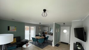 A modern living room with a sofa, a dining table, and a kitchen in the background. - Modern vacation home just 100 m from the Wangermeer with two bedrooms, smart TVs, fiber optics and terrace - perfect for families and those seeking relaxation. (Wangerland)