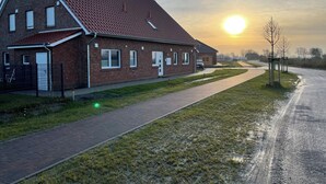 En byggnad av tegel med ett sluttande tak, en asfalterad uppfart och en gräsyta.