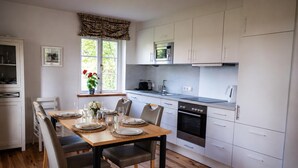 A modern kitchen with white cabinets, a built-in oven, and a microwave. - The Zugvogel vacation home offers a cozy first floor apartment in a quiet, secluded location near the North Sea - ideal for families and dog owners looking to relax in the fenced garden and natural surroundings. (Wangerland)