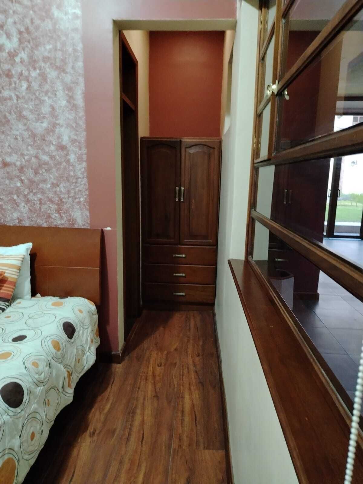 Une chambre à coucher avec un lit, une armoire en bois et une fenêtre.