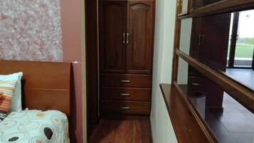 Un dormitorio con cama, armario de madera y ventana.