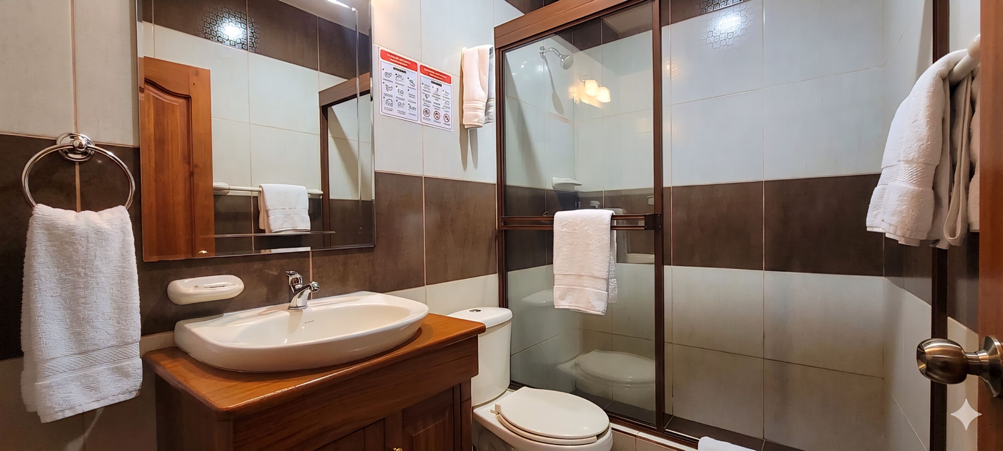 A bathroom with a sink, mirror, towel rack, and a glass shower enclosure.