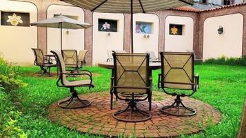 Un patio con una mesa redonda y sillas, rodeado por un borde de ladrillo.