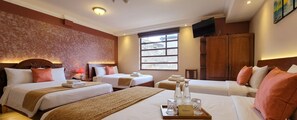 A hotel room with two beds, a TV, a window, and a wooden wardrobe.