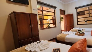 A hotel room with two beds, a wardrobe, a bedside table with a lamp, and a window with a view. - Hotel Pegasus (Cuenca)