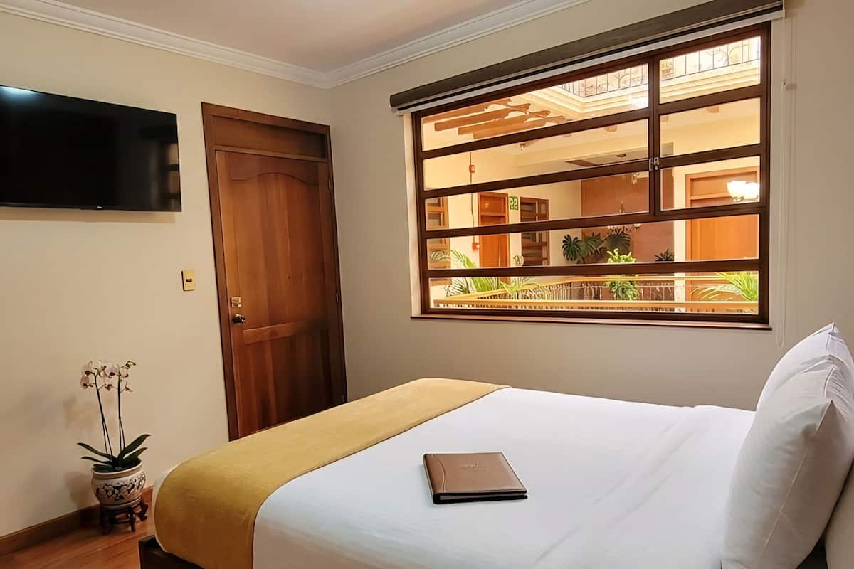 Une chambre dâhĂŽtel avec un lit, une tĂ©lĂ©vision, une fenĂȘtre donnant sur un paysage agrĂ©able et une porte.