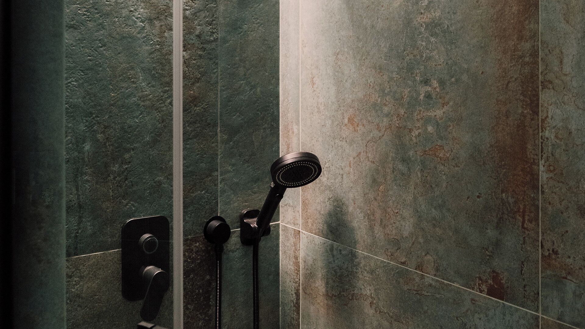 A shower with a handheld showerhead and a control knob.