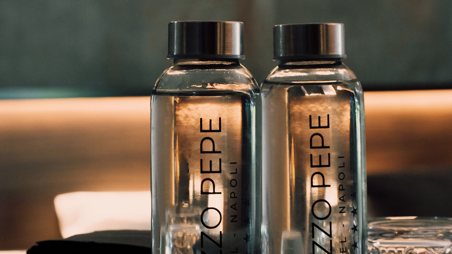 Dos botellas de vidrio transparente con la etiqueta 'ZAZZOPEPE NAPOLI' sobre una mesa.