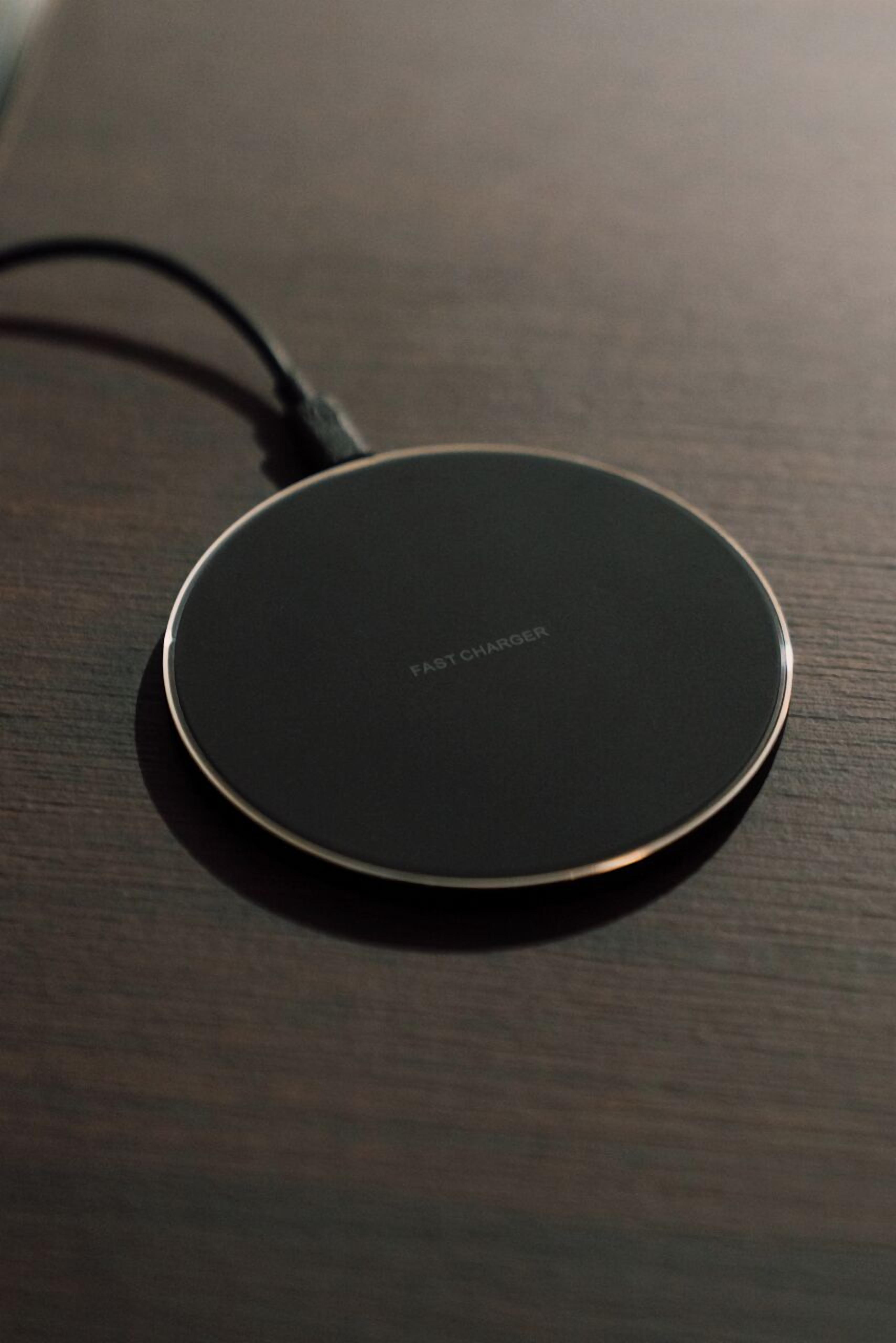A circular, black charging pad on a wooden surface.
