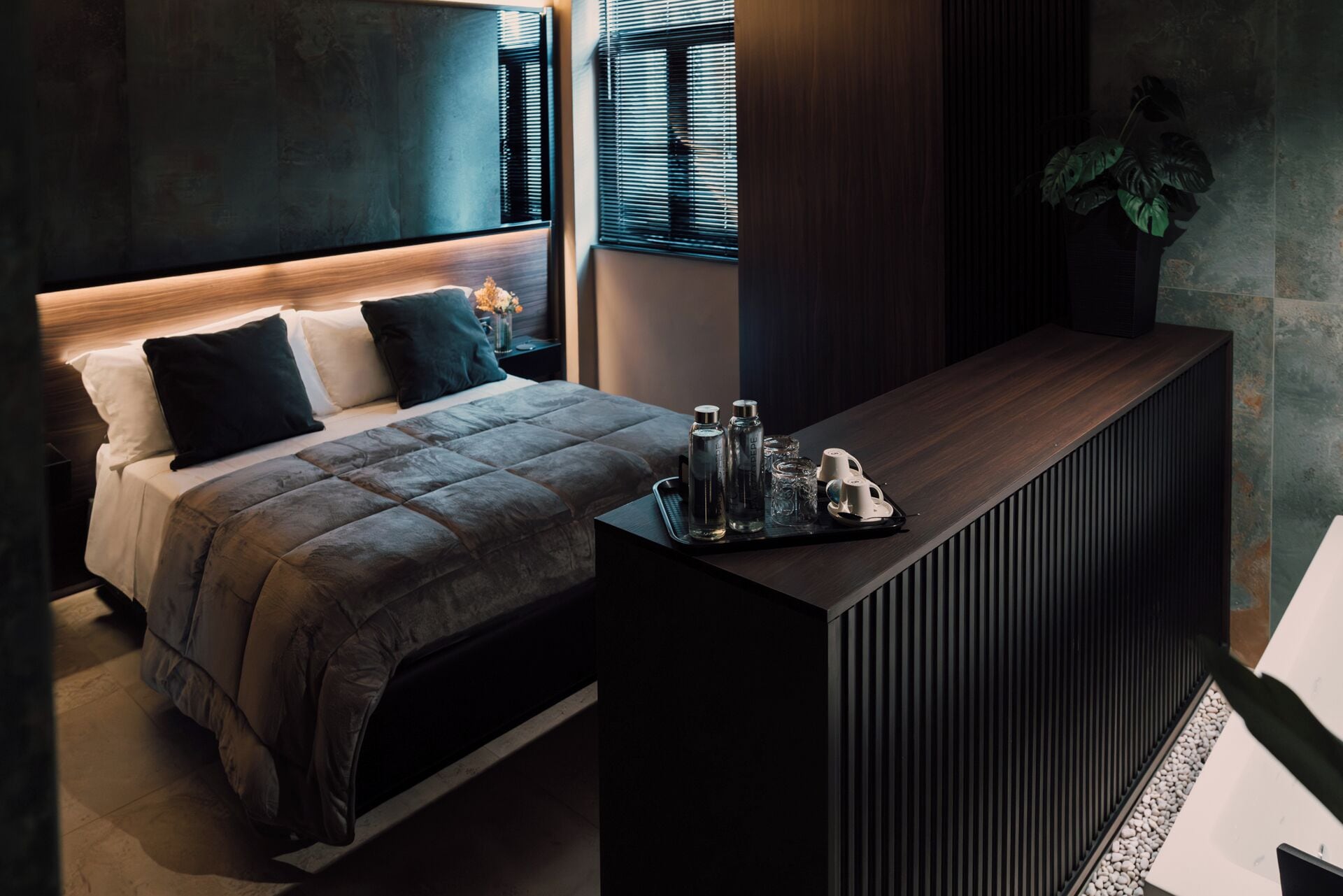 Un dormitorio moderno con cama, mesita de noche y una planta.