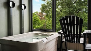 Une salle de bain avec une baignoire, une chaise et une fenêtre donnant sur les arbres.