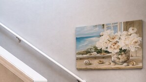 En trappa med mattbeklädda trappsteg, ett vitt handledare och en målning av blommor på väggen.