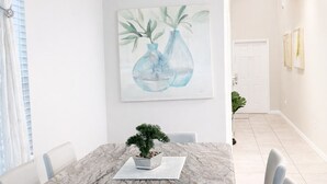 En matplats med ett bord i marmor, sex stolar, en krukväxt, en kristallkrona och en tavla på väggen.