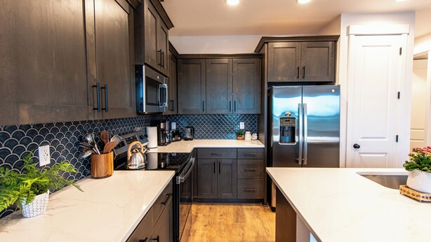 Una cocina moderna con armarios de madera oscura, electrodomésticos de acero inoxidable y un salpicadero de azulejos.