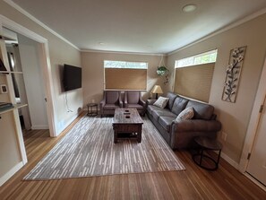 A living room with a sofa, a coffee table, and a TV mounted on the wall.