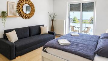 Una camera da letto con un letto, un divano, uno specchio grande e vista sull'esterno.