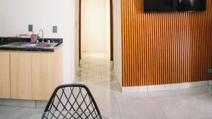 Moderni keittiö, jossa on sisäänrakennettu televisio, ruokailutila tuoleineen sekä käytävä.