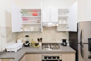 Une cuisine moderne avec des meubles blancs, une cuisinière à gaz, un réfrigérateur et un four encastré.