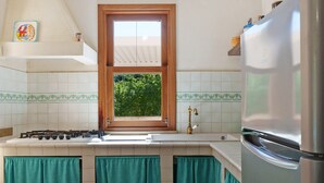 A kitchen with a gas stove, a sink, a window, and a refrigerator. - Villa 'Diego' with Sea View, Wi-Fi and Air Conditioning (Favignana)