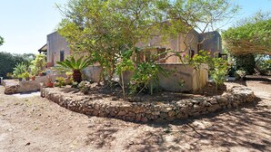 A house with a stone wall garden, a tree, and potted plants. - Villa 'Diego' with Sea View, Wi-Fi and Air Conditioning (Favignana)