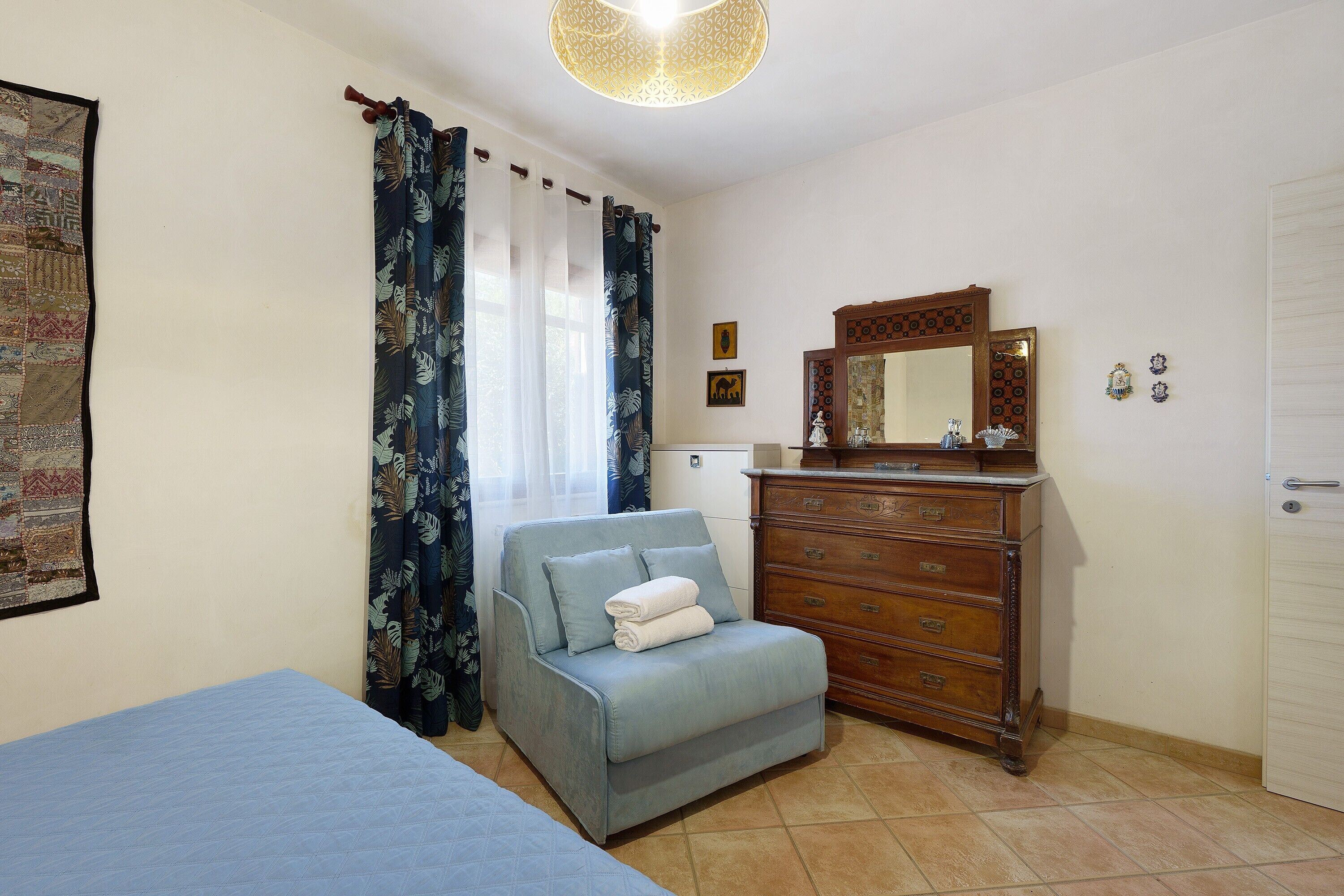 A bedroom with a bed, a sofa, a dresser, a mirror, and curtains.