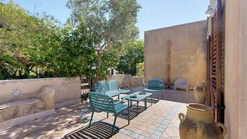An outdoor patio with metal chairs and tables, a large ceramic pot, and a white plastic chair.