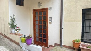 A building with a wooden door, potted plants, and a small shelf with items. - riMINI house - One Bedroom Apartment, Sleeps 2 (Rimini)