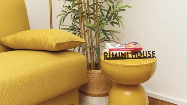 A yellow sofa, a bamboo plant, and a small table with a book titled 'RIMINI HOUSE'. - riMINI house - One Bedroom Apartment, Sleeps 2 (Rimini)