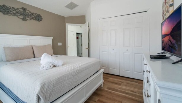 Ein Schlafzimmer mit Bett, Deckenventilator, Tür und Fernseher.
