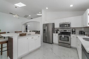 A modern kitchen with white cabinetry, a stainless steel refrigerator, an oven, and a microwave. - 5-Bed Villa w/ Private Pool (Davenport)