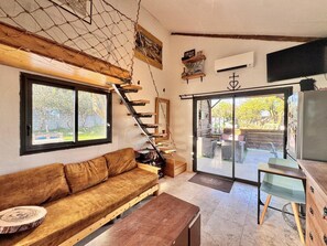 Ein gemütliches Wohnzimmer mit einer Holztreppe, einer Couch und einer Schiebetür zu einem Außenbereich.