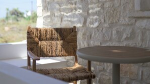 Un mur de pierre, une chaise en osier et une table ronde.