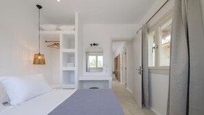 Une chambre à coucher comprenant un lit, une armoire, un miroir et un luminaire suspendu.
