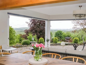 Un coin repas avec une table, des chaises et un vase de fleurs.