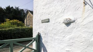 A white wall with a 'BARN HOUSE' sign, a green gate, and a hedge in the background. - Barn Howe (Kendal)