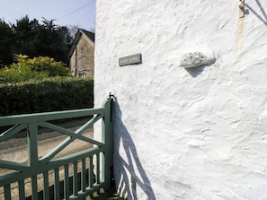 A white wall with a 'BARN HOUSE' sign, a green gate, and a hedge in the background.