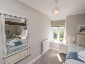 A bedroom with a large mirror, a bed, a nightstand, a window with a view, and a hanging light fixture.
